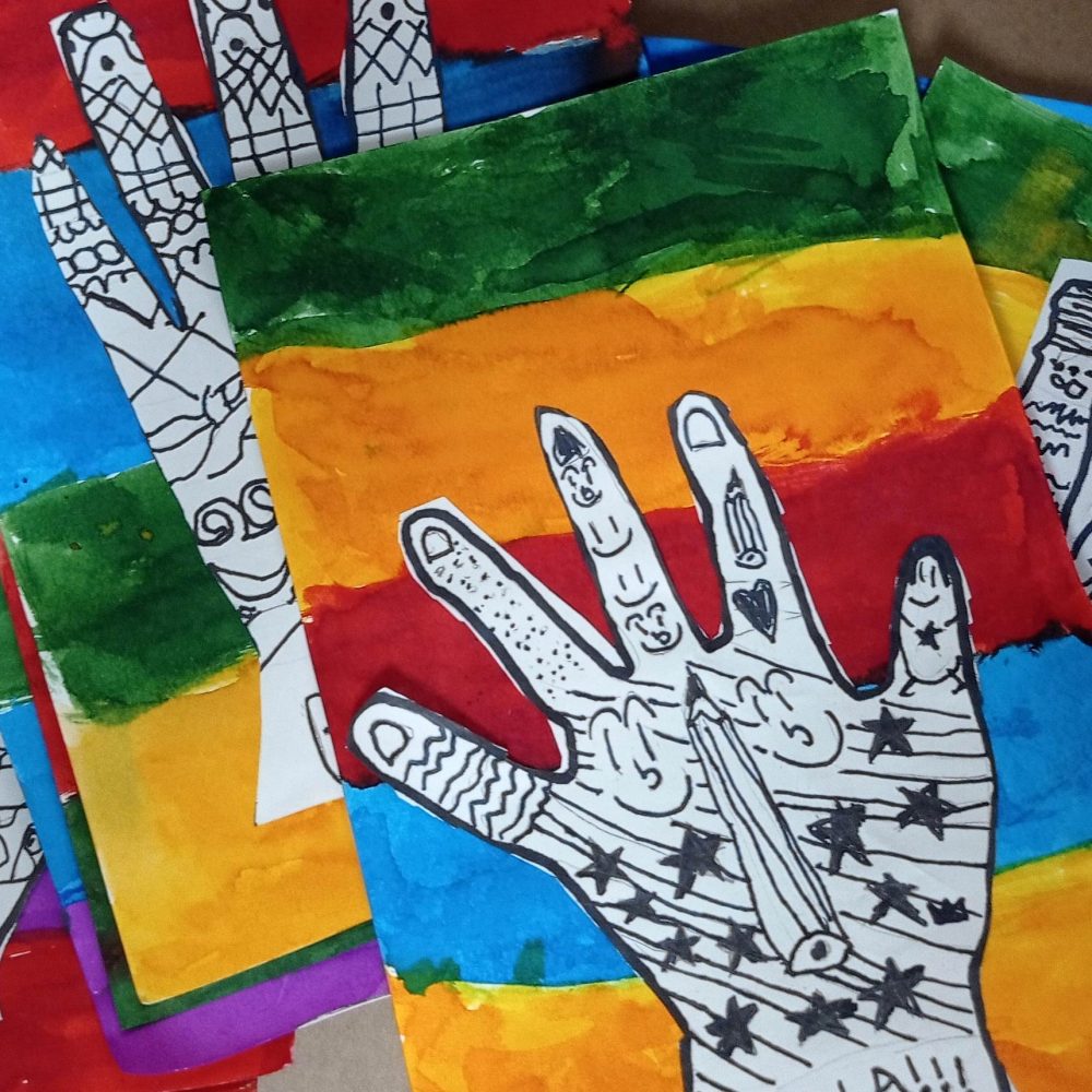 Mans pintant dibuixos de colors sobre una taula